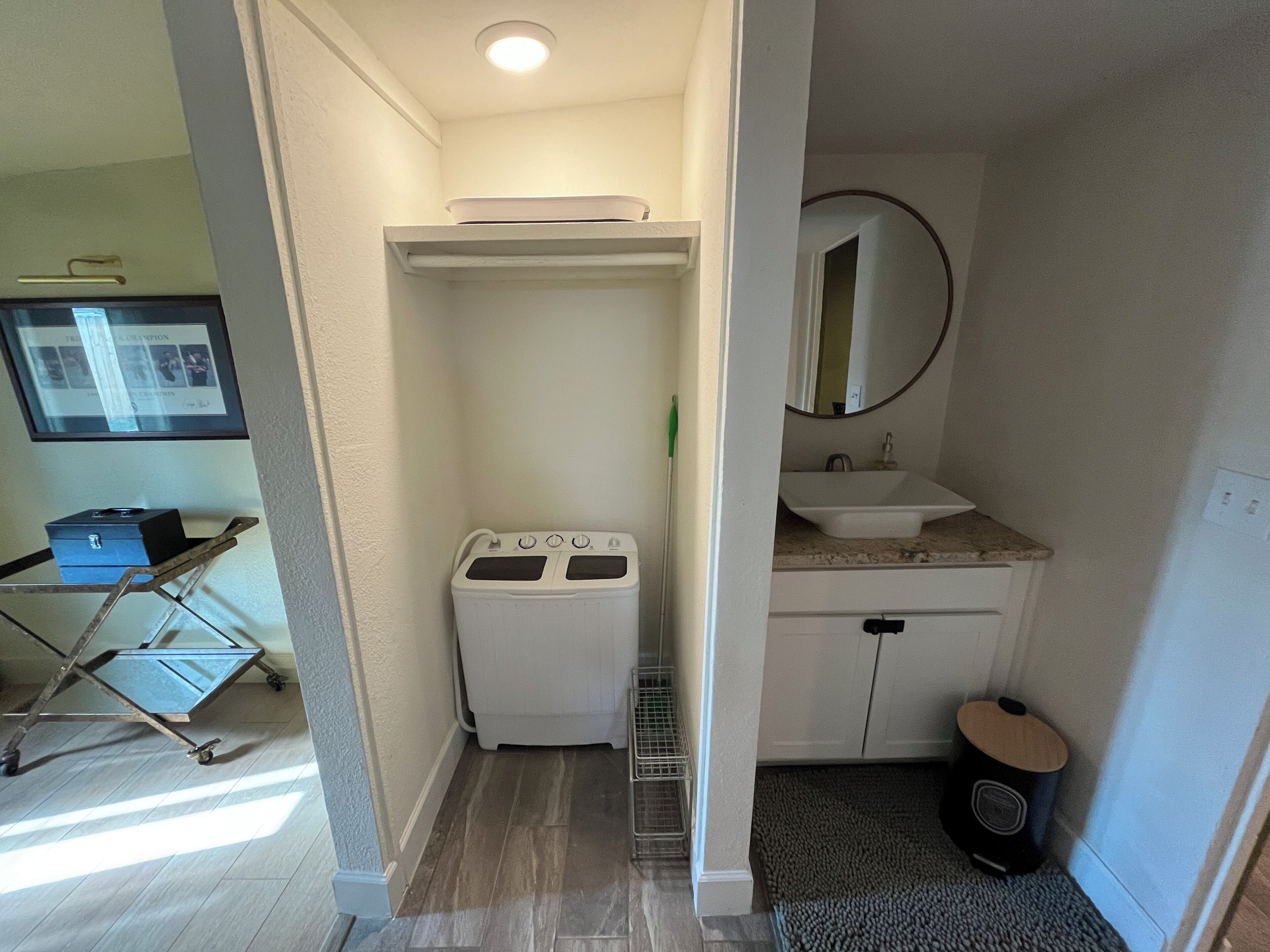 Une petite salle de bain équipée d’un lave-linge, d’un lavabo et d’un miroir.