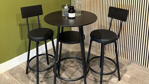 Ruokailutila, jossa on pyöreä pöytä ja kaksi tuolia, riippuvalaisin ja kuvioitu seinä.