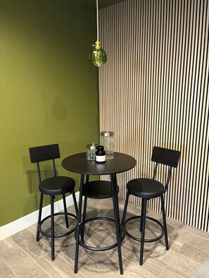 A dining area with a round table and two chairs, a hanging light fixture, and a textured wall. - Cozy bungalow in Central Phoenix near stadiums, hospitals, & restaurants (Phoenix)