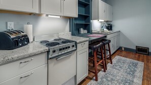 A kitchen with white cabinets, a gas stove, a toaster, and a coffee maker. - The Downtown, Stay in the Heart of Mossy Creek (Jefferson City)