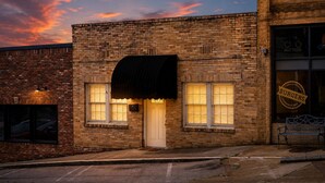 A brick building with a white door, windows with blinds, and a sign for 'BURGERS' on the right. - The Downtown, Stay in the Heart of Mossy Creek (Jefferson City)