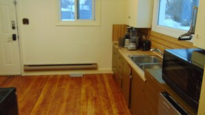 A compact kitchen with a built-in microwave, a sink, and a window above the countertop. - Just You Vacation Home - Main floor use (Gilbert Plains)