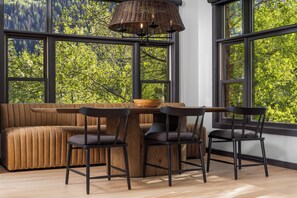 Ein modernes Interieur mit einer Couch, zwei Sesseln, einem Tisch und einem großen Fenster mit Blick auf Bäume.