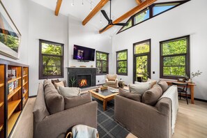 A spacious living room with a fireplace, large windows, a television, and a cozy seating area. - Luxury Remodeled 4BR Telluride Home | Hot Tub, Walk to Gondola & Main St | Sleeps 12 (Telluride)