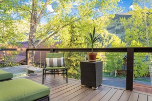 Eine Holzterrasse mit Whirlpool, einem Sessel mit Kissen und einem Blumentopf.
