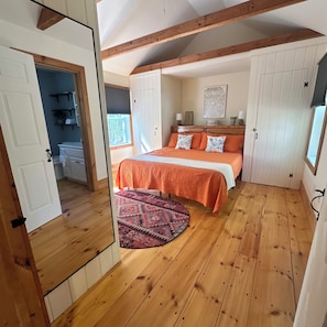 Ein Schlafzimmer mit einem Bett, Holzboden und einem Fenster.
