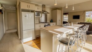 Una cocina moderna con una isla central, taburetes de bar y un área de comedor con sofá.