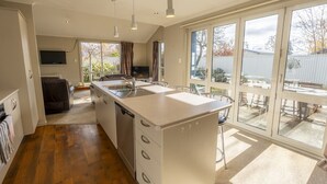 Una cocina moderna con una isla central, ventanas amplias y una zona de comedor con mobiliario de exterior.