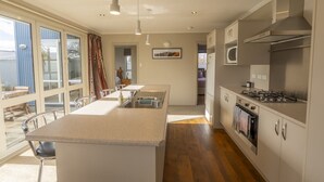 Una cocina moderna con una isla central, electrodomésticos de acero inoxidable y ventanas amplias.