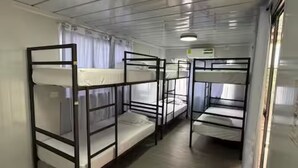 Une chambre de dortoir avec des lits superposés, un tapis rouge et une porte blanche.