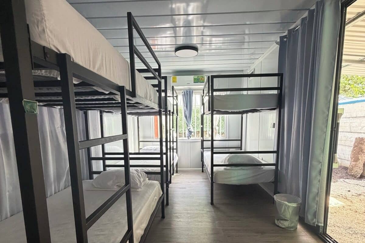 A corridor with bunk beds, a window, and a door leading outside.