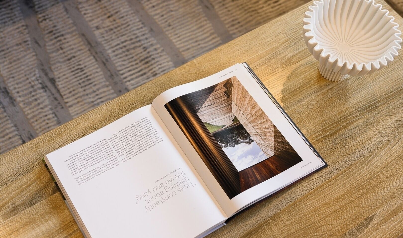 An open book with a photograph of a wooden structure and a white object on a wooden surface.