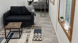 A compact room with a bunk bed, a sofa, a small table, and a large window. - Peaceful Montana Retreat near Glacier National Park (Fortine)