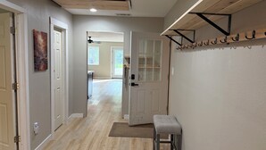 A hallway with a bench, a door, and a shelf with hooks. - Peaceful Montana Retreat near Glacier National Park (Fortine)