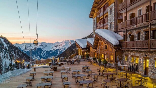 A wooden building with a balcony, outdoor seating area, and a view of snow-covered mountains. - Hotel Carlina Belle Plagne (La Plagne-Tarentaise)