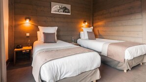 A room with two beds, wooden walls, and wall-mounted lights. - Hotel Carlina Belle Plagne (La Plagne-Tarentaise)