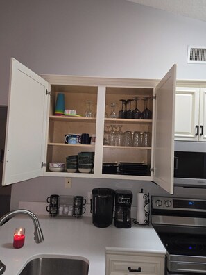 A kitchen with open cabinets, a sink, a stove, and a microwave. - Delightful 2-bedroom condo with AC in Myrtle Beach (Myrtle Beach)