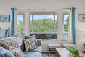 Ein Zimmer mit großem Fenster, einer Couch, einer Bank und einem kleinen Tisch.