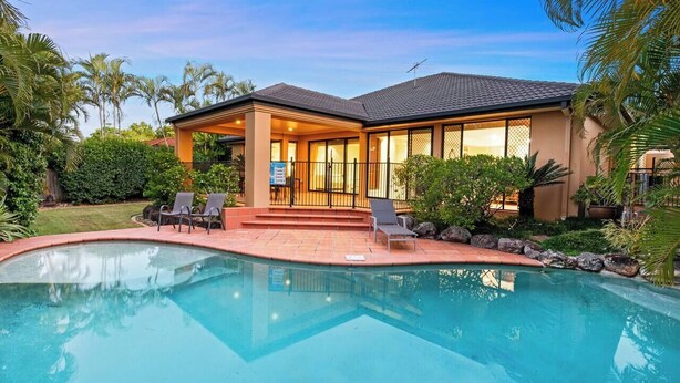 Una casa con piscina, un patio cubierto y vistas del entorno verde.