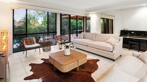 Un salón amplio con sofá, sillones, una mesa de centro y un piano.