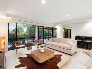 A spacious living room with a sofa, chairs, a coffee table, and a piano. - Artistic Retreat | Privacy Pool Patio WFH Perfect (Parkinson)
