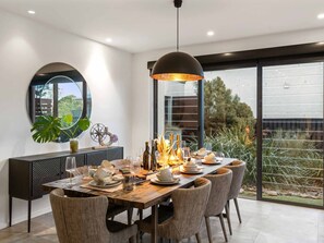 Ein moderner Essbereich mit einem runden Tisch, Stühlen und einem großen Fenster mit Blick auf Grünflächen.