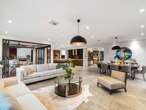 Ein modernes Wohnzimmer mit einer Couch, einem Sessel, einem Couchtisch und einem Essbereich mit einem runden Tisch.