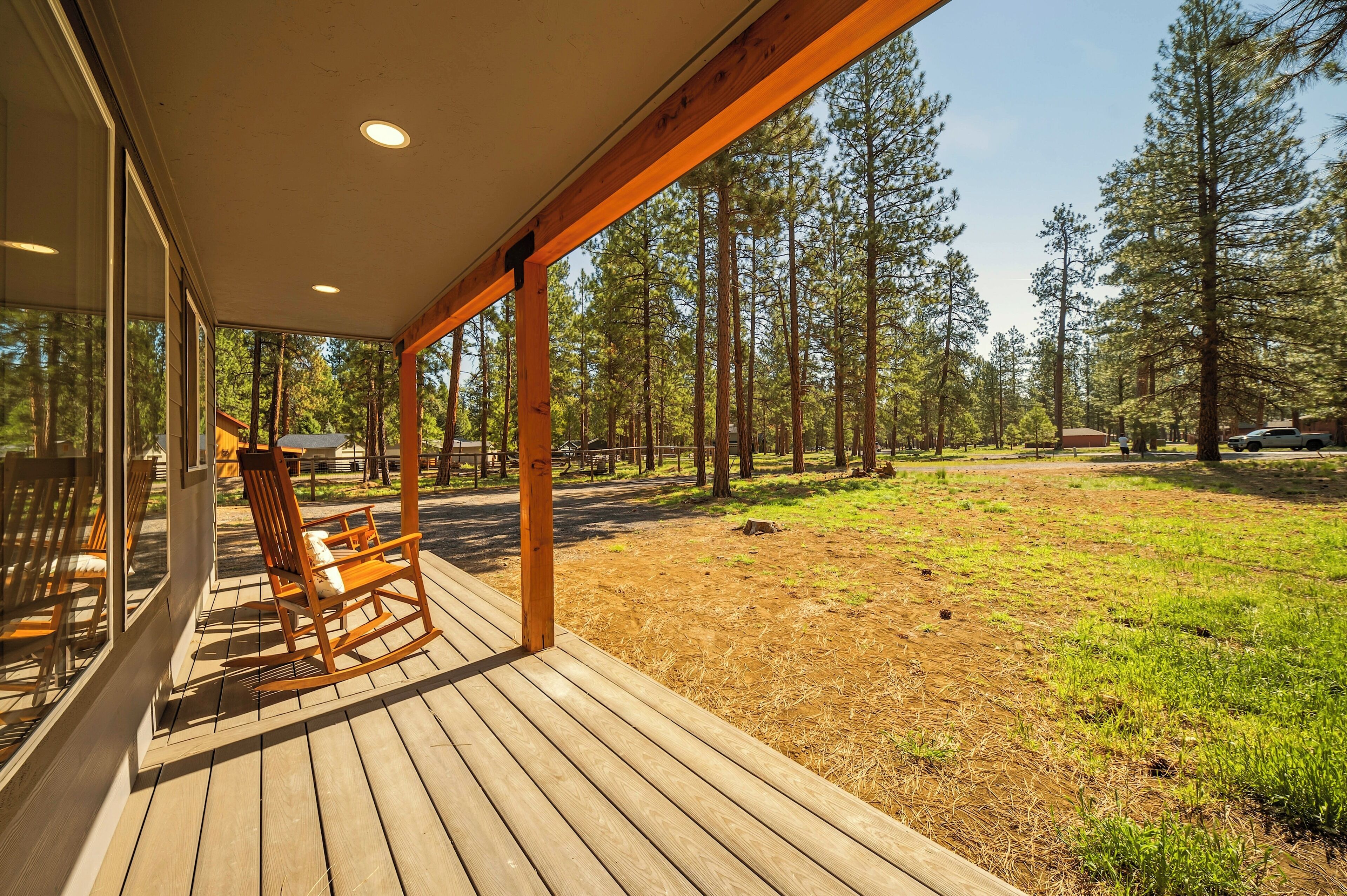 A wooden deck with a rocking chair and a covered area with large windows.