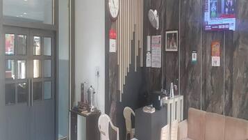 A reception area with a reception desk, a clock, a television, and a seating area with a sofa and chairs.
