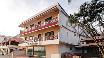 A multi-story hotel with a balcony on the second floor, a sign for 'The Waters Edge Beach Resort,' and a palm tree in the foreground.