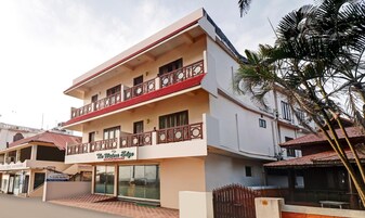 Un hotel de varios pisos con un balcón en el segundo piso, un letrero que dice 'The Waters Edge Beach Resort' y una palmera en primer plano.