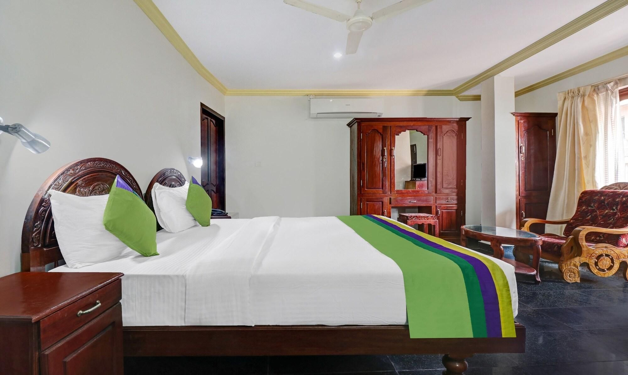 Quarto de hotel com cama, mobiliário de madeira, ventoinha no teto e ar condicionado.
