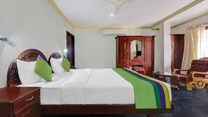 A hotel room with a bed, wooden furniture, a ceiling fan, and an air conditioning unit. - OYO 6031 The Waters Edge Beach Resort (Neyyattinkara)