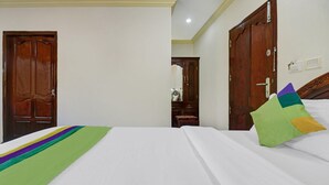A hotel room with a bed, two wooden doors, a mirror, and a nightstand. - OYO 6031 The Waters Edge Beach Resort (Neyyattinkara)
