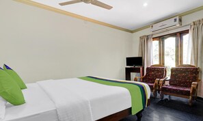 A hotel room with a bed, a television, two chairs, and a window with curtains. - OYO 6031 The Waters Edge Beach Resort (Neyyattinkara)
