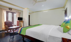 Quarto de hotel com cama, televisão, escrivaninha e cadeira.