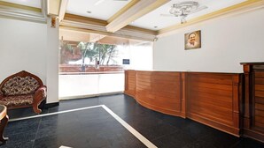 A reception area with a wooden reception desk, a patterned armchair, and a ceiling fan. - OYO 6031 The Waters Edge Beach Resort (Neyyattinkara)