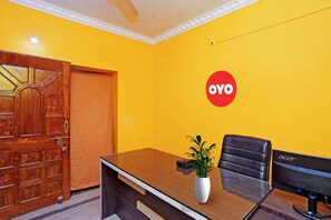 A conference room with a wooden table, a black leather chair, a white vase with a plant, and an Acer monitor. - 16363 Advik Cottage (Bhubaneshwar)
