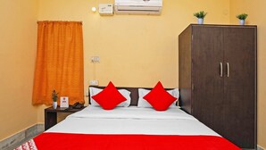 Quarto de hotel com uma cama, guarda-roupa, ar condicionado e um vaso de plantas.