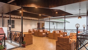 A spacious outdoor seating area with wicker furniture and potted plants. - Udaan Hotels Alpine Resort, Gangtok (Gangtok)