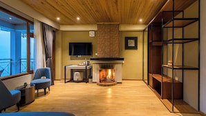 A modern living room with a fireplace, a television, and a balcony view. - Udaan Hotels Alpine Resort, Gangtok (Gangtok)