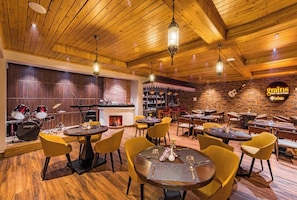 A restaurant with wooden ceilings, yellow chairs, and a brick wall. - Udaan Hotels Alpine Resort, Gangtok (Gangtok)