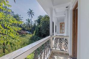 A balcony with a view of greenery and a building in the background. - The Sequeira By Madhu And Sons (Majorda)