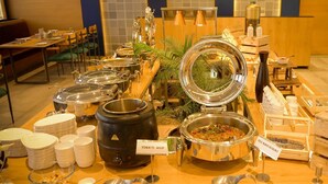 A buffet setup with various food containers, including a large pot labeled 'TOMATO SOUP' and a smaller pot labeled 'VEG MANCURIAN.' - Pinnacle Grand Hotel Nad Banquet (Ahmedabad)