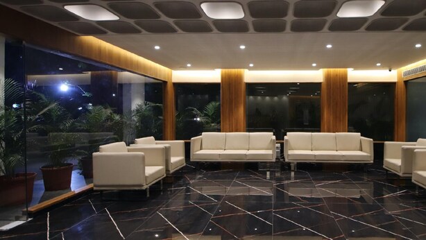 A modern lobby with a marble floor, white sofas, and a glass wall with a night view. - Pinnacle Grand Hotel Nad Banquet (Ahmedabad)