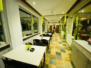 A hotel corridor with tables and chairs, a reception desk, and potted plants. - 7 Monkey Hills Resort By Spicy Mango (Paud)