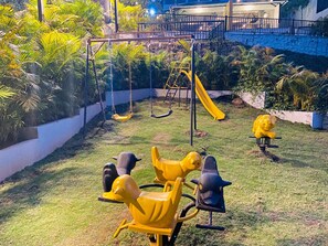 A playground with swings, a slide, and animal-shaped seats. - 7 Monkey Hills Resort By Spicy Mango (Paud)