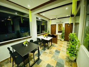 A dining area with a table and chairs, a reception desk, and potted plants. - 7 Monkey Hills Resort By Spicy Mango (Paud)