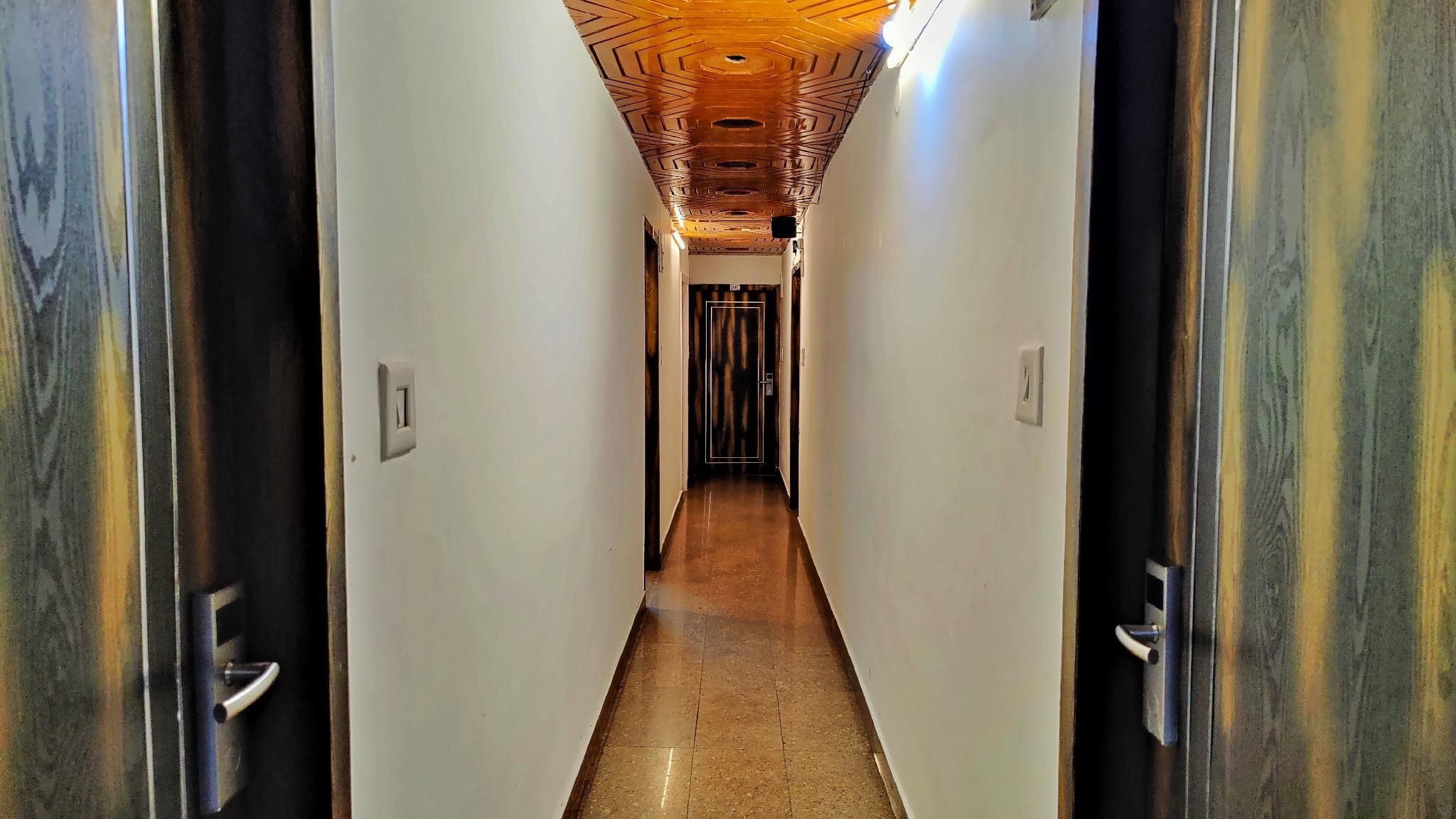 A hallway with a wooden ceiling, white walls, and a tiled floor.