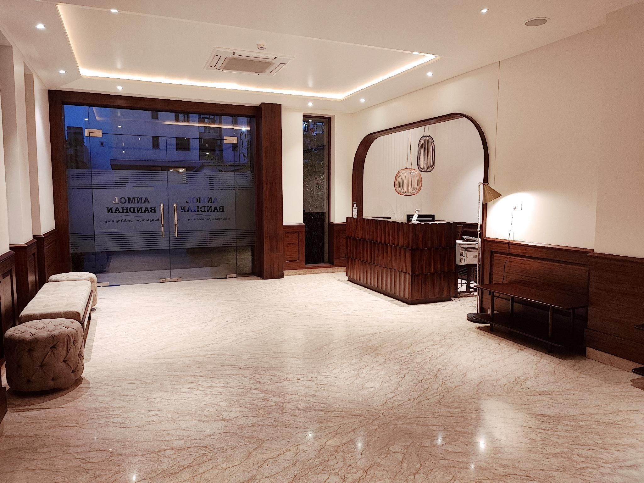 A hotel lobby with a reception desk, seating area, and a large glass door entrance.